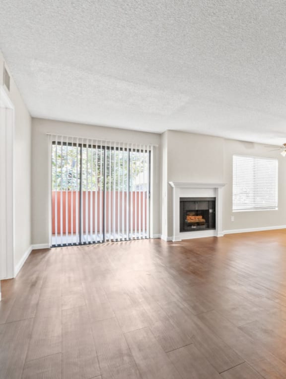 an empty living room with a fireplace and a ceiling fan