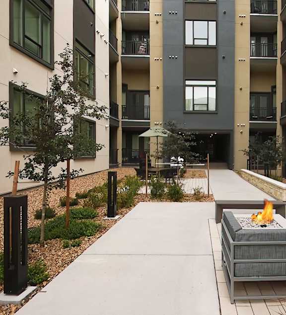 A modern outdoor seating area with a fire pit in the middle.