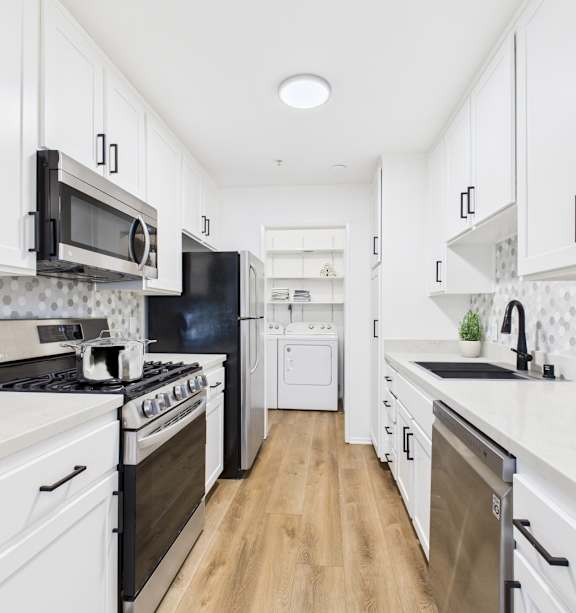 A kitchen with black and white appliances and white cabinets.