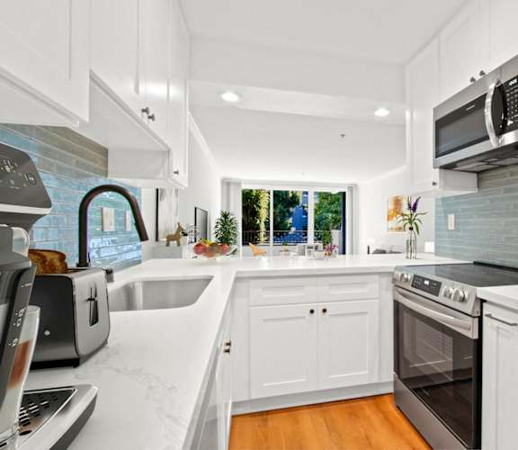 a kitchen with white cabinets and stainless steel appliances and a window