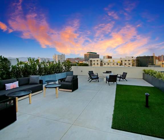 a rooftop patio with a city skyline in the background and grass