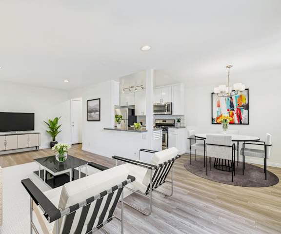 A modern living room with a television, a coffee table, and a dining table.