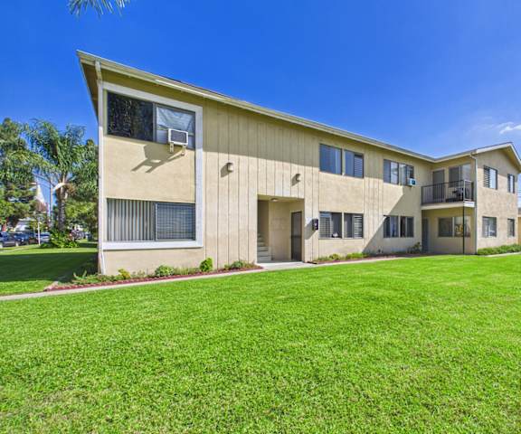 A beige building with a green lawn in front.