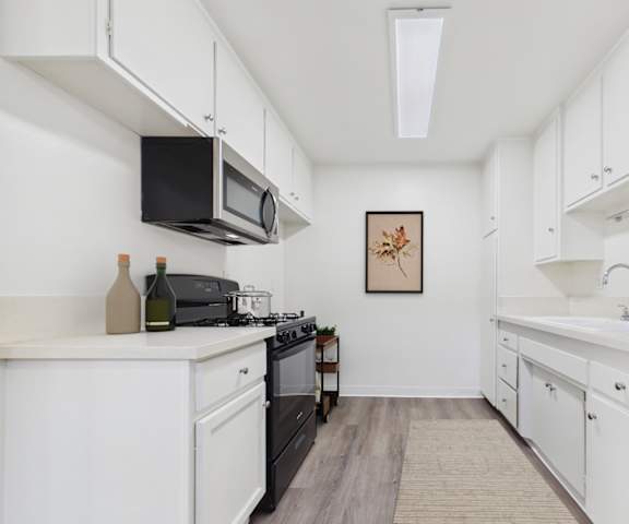 A kitchen with white cabinets and a black stove top oven.