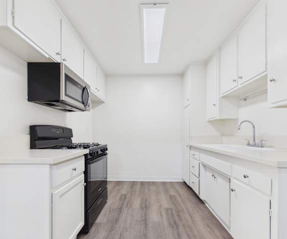 A kitchen with white cabinets and a black microwave.