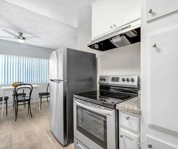 A kitchen with a refrigerator, oven, and stove.