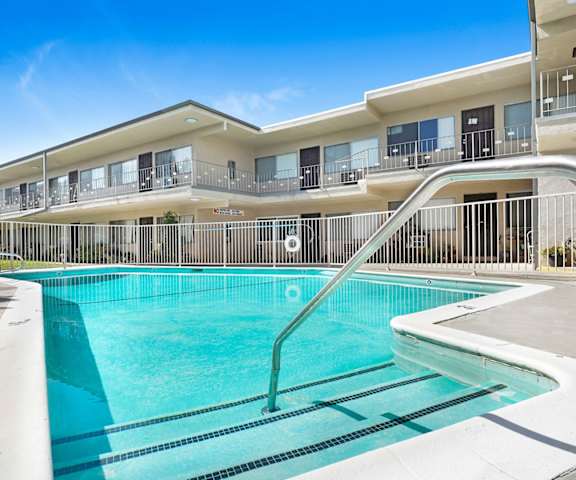 A swimming pool in front of a building with a metal railing.