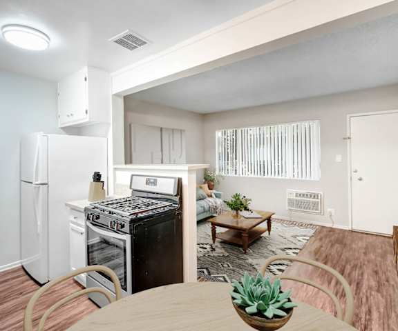 an open kitchen and living room with a dining table and a refrigerator