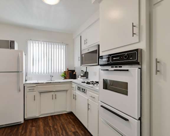 an empty kitchen with white appliances and white cabinets