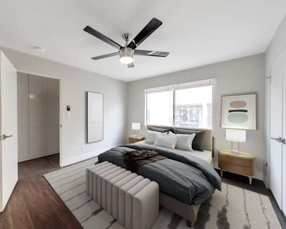 A modern bedroom with a large bed and a ceiling fan.
