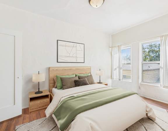 A bedroom with a large bed and a window with curtains.