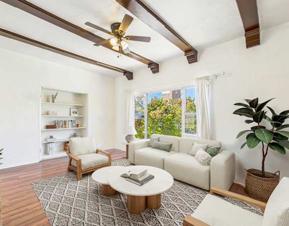 A living room with a white couch, a coffee table, and a ceiling fan.