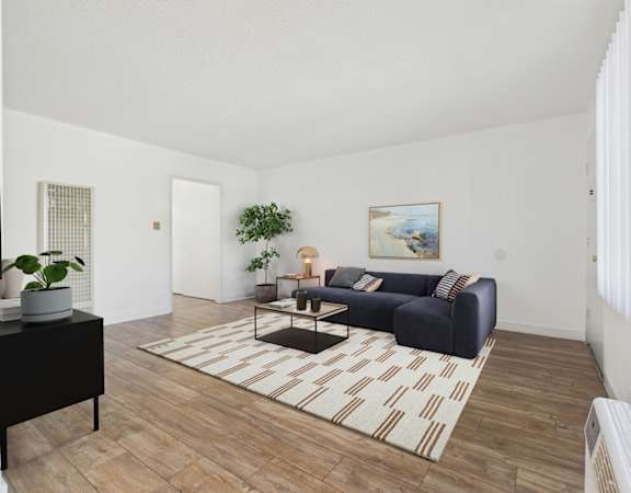 A living room with a blue couch and a painting on the wall.