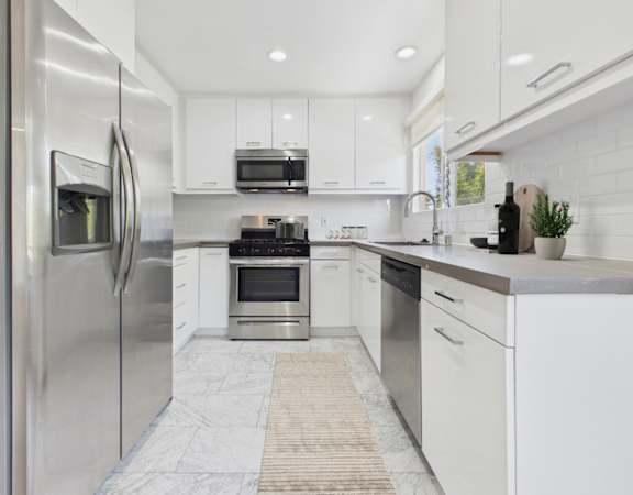 A modern kitchen with white cabinets and stainless steel appliances.