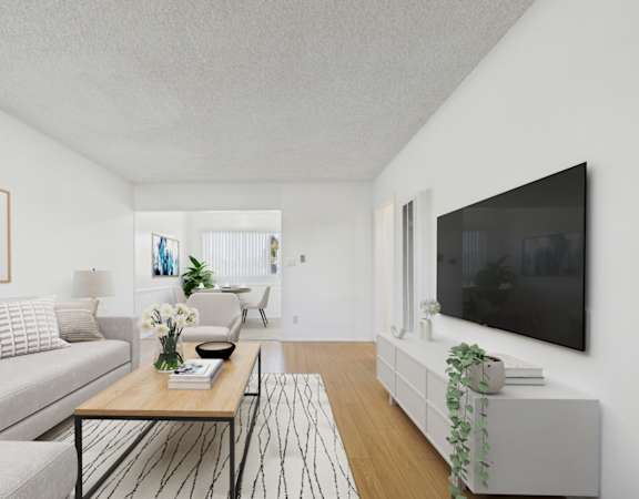A living room with a grey couch, a coffee table, and a flat screen TV mounted on the wall.