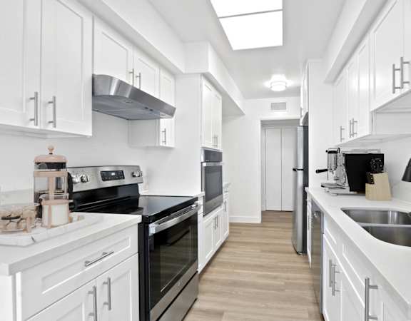 a white kitchen with black appliances and white cabinets
