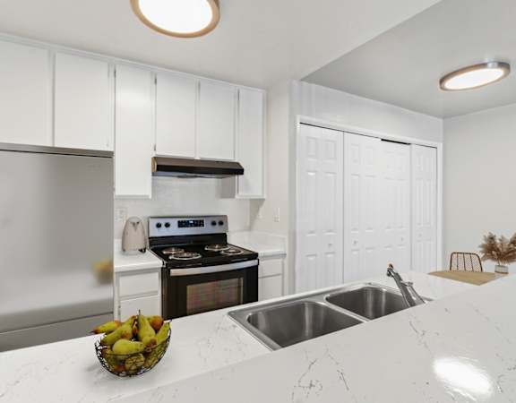 a white kitchen with stainless steel appliances and a counter top