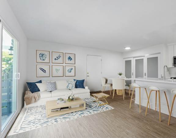 a living room with a couch and a kitchen with a breakfast bar and a window