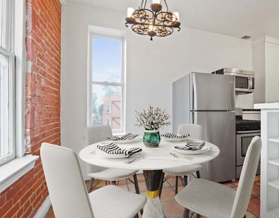 a dining room with a table and chairs and a kitchen with a refrigerator