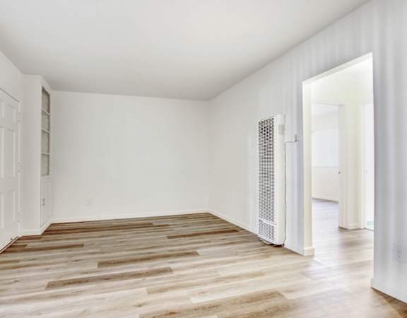 a bedroom with hardwood floors and white walls
