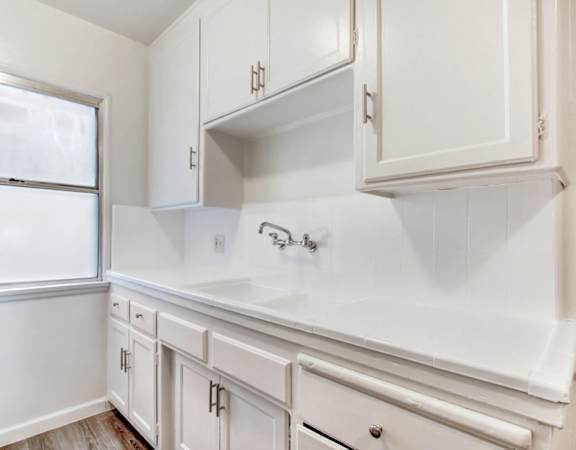 a kitchen with white cabinets and a window