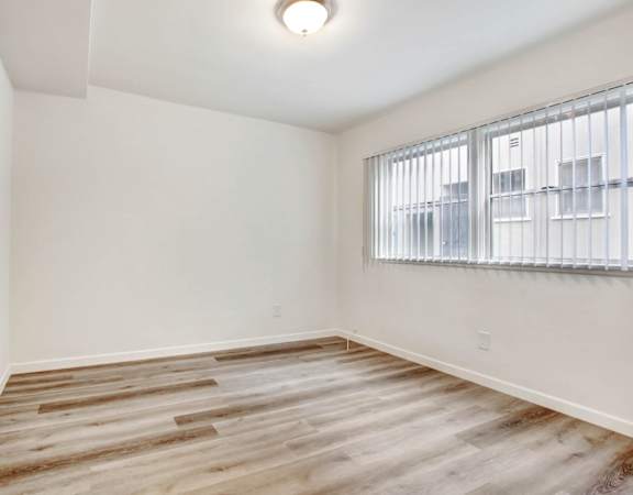a bedroom with hardwood flooring and a large window