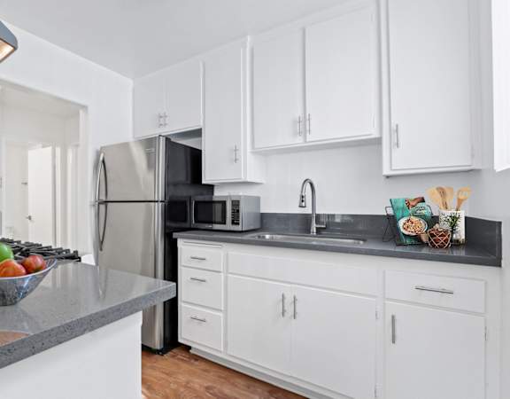 a kitchen with white cabinets and a stainless steel refrigerator