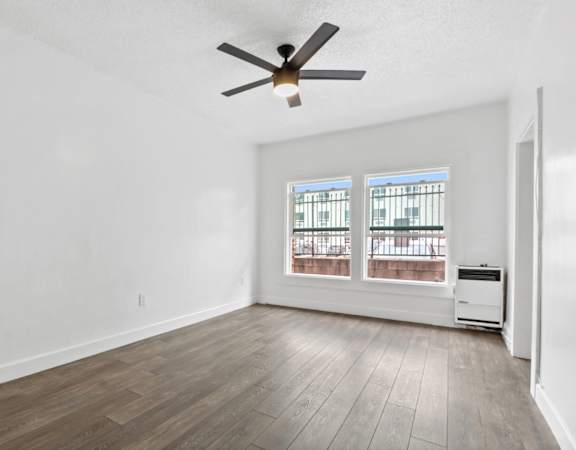 a bedroom with hardwood floors and white walls