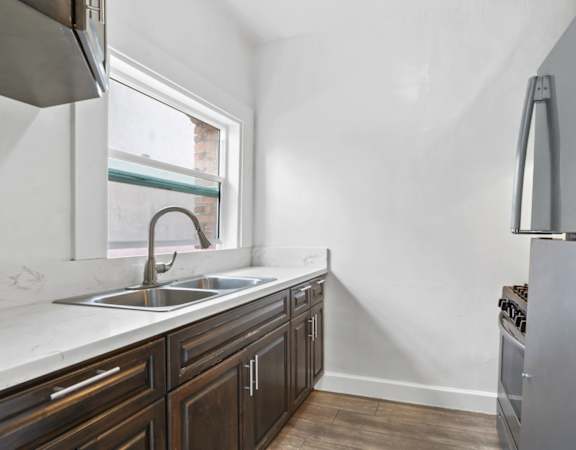 a kitchen with white walls and wooden cabinets