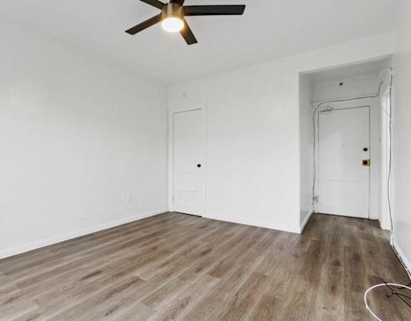 a bedroom with hardwood floors and white walls