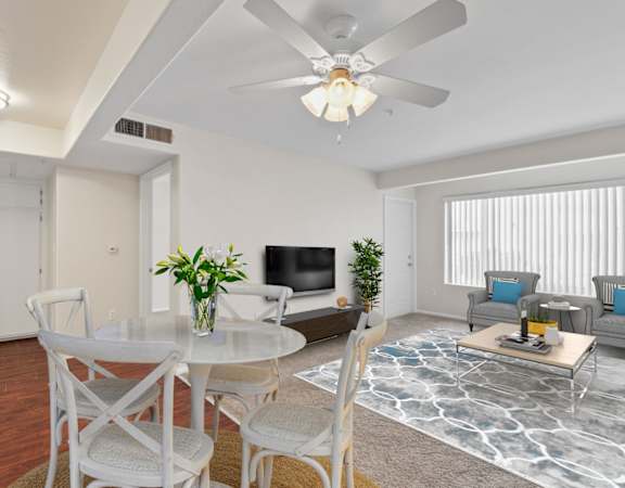 a living room with white furniture and a ceiling fan