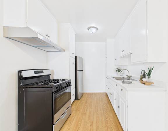 A modern kitchen with white cabinets and a wooden floor.
