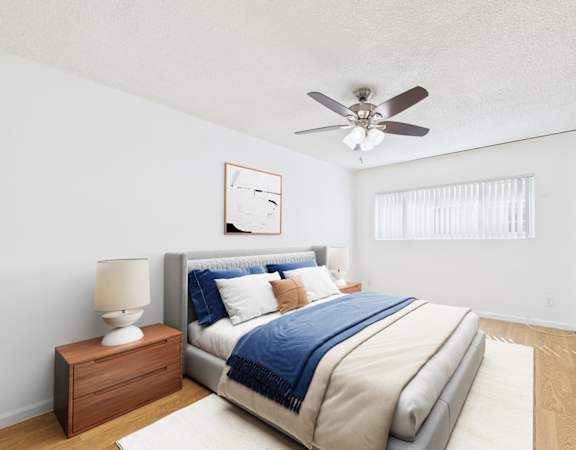 A bedroom with a bed, a nightstand, and a ceiling fan.