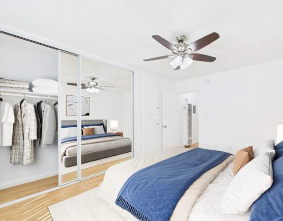 A bedroom with a bed, a ceiling fan, and a closet with clothes hanging.