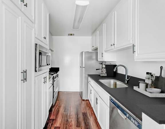 a kitchen with white cabinets and a wood floor