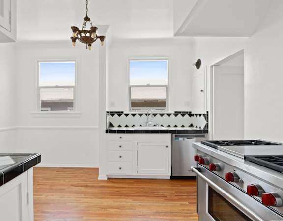 a white kitchen with a stove and a window