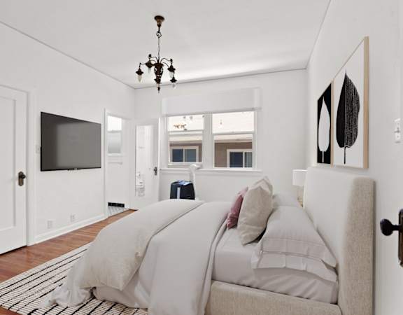 a white bedroom with a bed and a tv