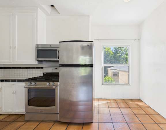 A kitchen with a stainless steel refrigerator, oven, and microwave.