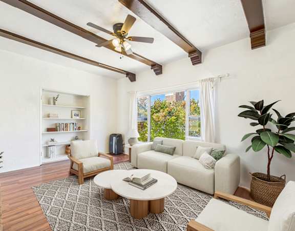 A living room with a white couch, a coffee table, and a ceiling fan.
