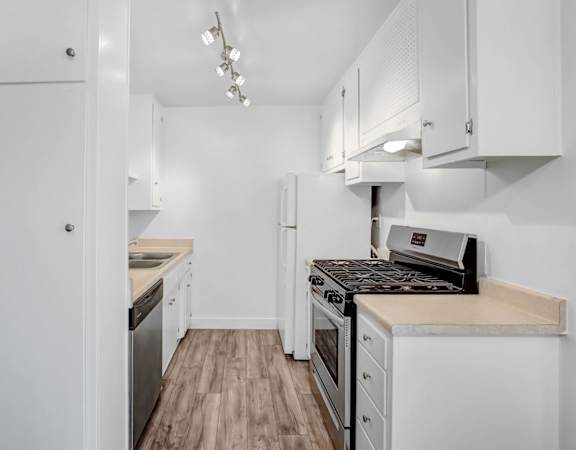 a renovated kitchen with white cabinets and white appliances and wood floors