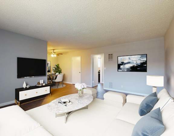 A living room with a white couch and a flat screen TV mounted on the wall.