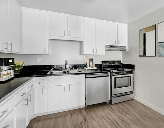 an empty kitchen with white cabinets and stainless steel appliances