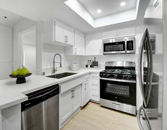a white kitchen with stainless steel appliances and white counter tops