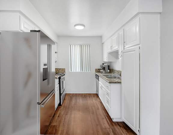 a renovated kitchen with white cabinets and stainless steel appliances