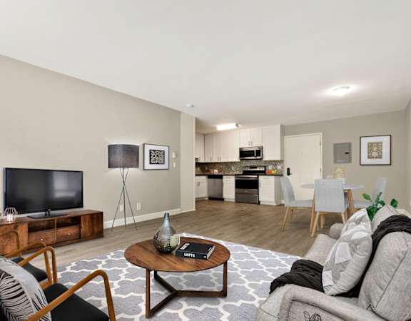 a living room with a tv and a kitchen in the background