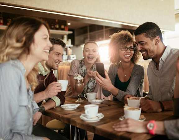 a group of people sitting around a table talking and laughing