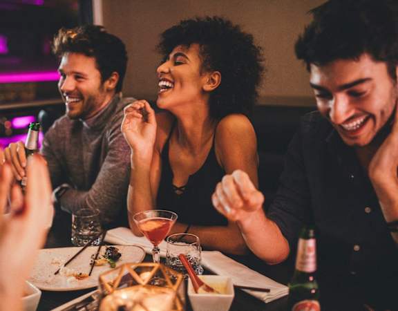 a group of people sitting at a table laughing and eating at a restaurant