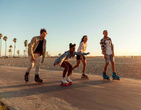 a group of people riding skateboards on the beach
