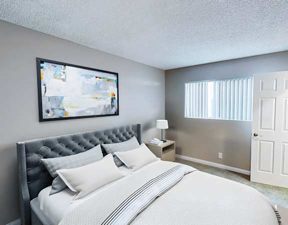 A bedroom with a large bed and a painting on the wall.
