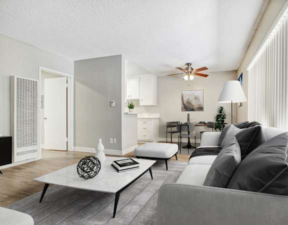 A modern living room with a grey couch, a white coffee table, and a ceiling fan.